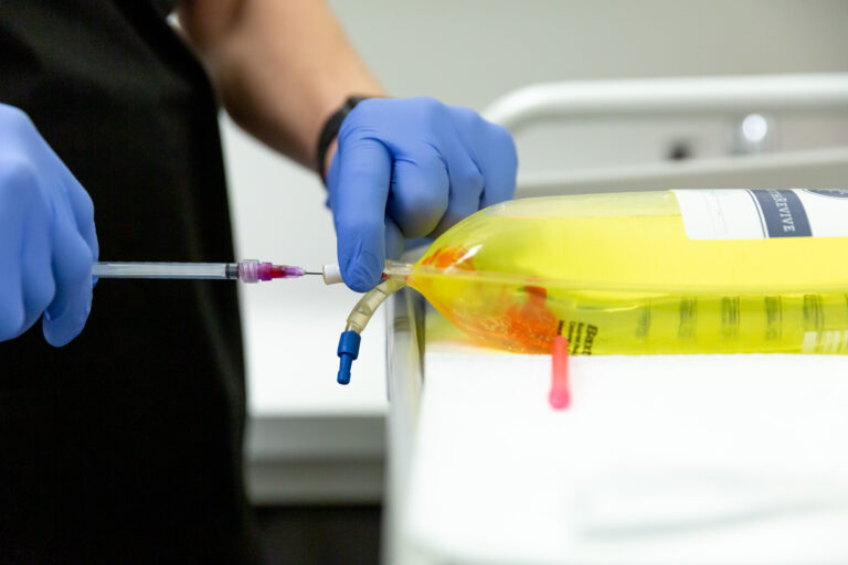 A nurse with blue gloves prepares an IV bag for an immune system booster in Nashville