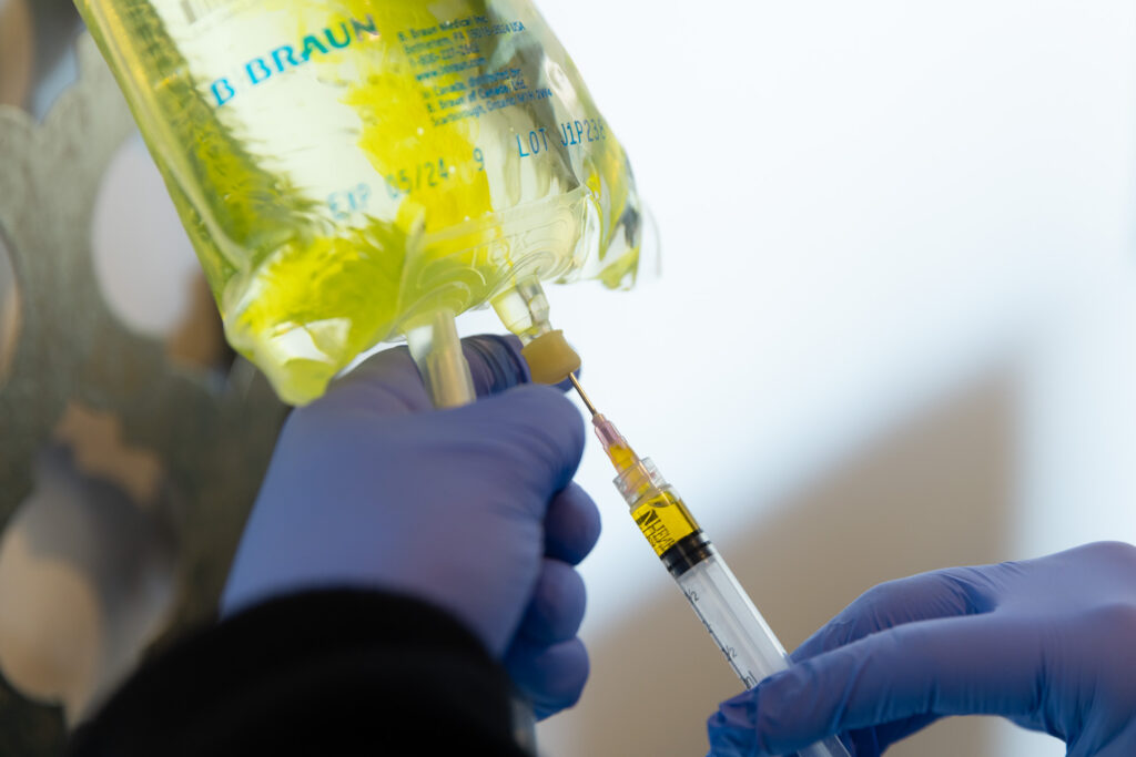 gloved hand holds IV bag as post procedure for undereye filler in Nashville