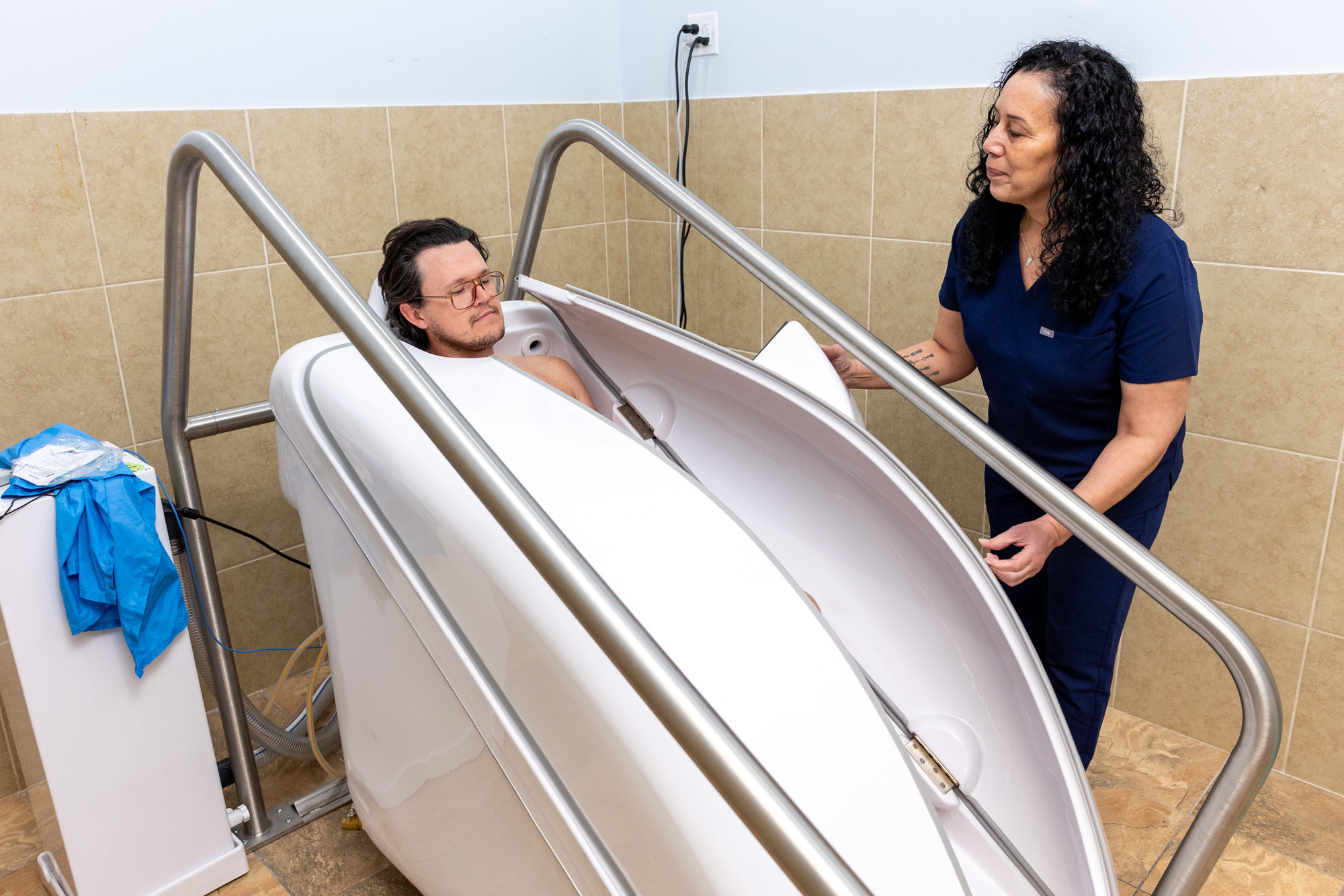 A nurse helps a patient get comfortable in the HOCATT sauna chamber after he asks how to reduce inflammation in the body