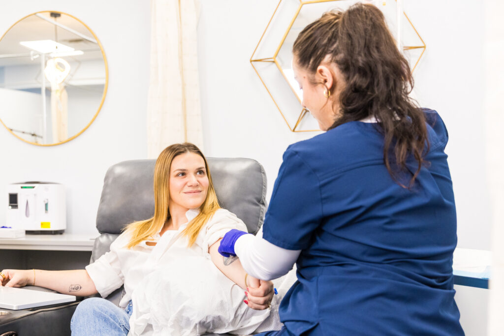 A registered nurse administers an IV to a seated woman for migraine relief in Nashville.