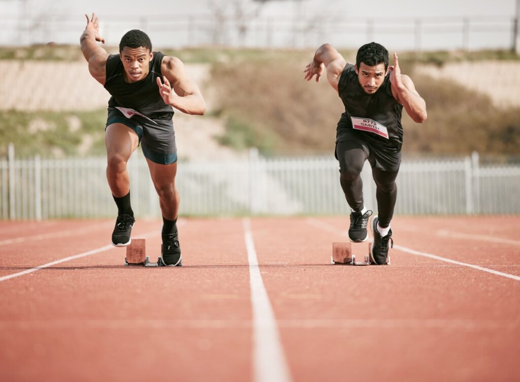 Two young athletic men just starting a foot race on a running track. They are prepare for this grueling contents because they had hydration during mobile IV therapy near Brentwood.