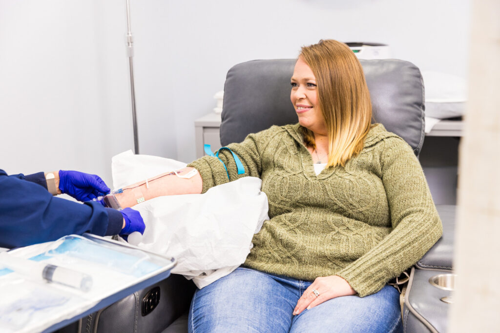 A female client sits in a recliner and smiles at a nurse who administers her infusion for joint pain therapy in Nashville.
