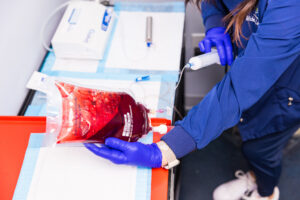 A gloved nurse uses a syringe connected to IV tubing and an IV bag.