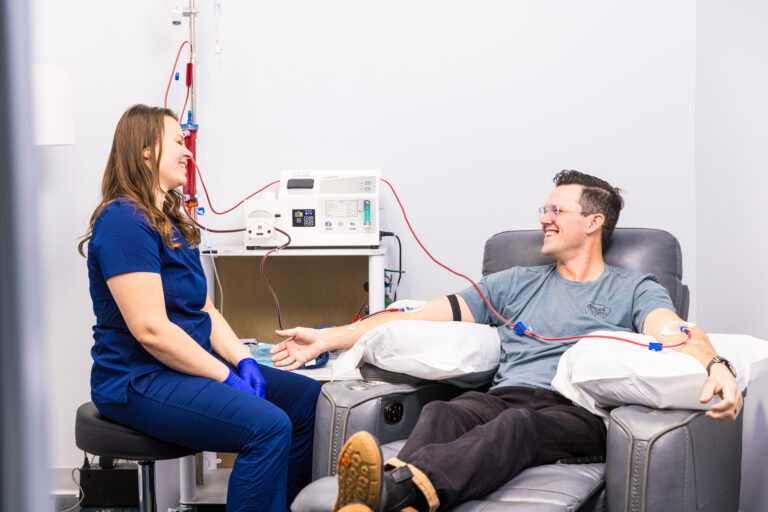 A nurse and client both seated as the client receives EBOO therapy.